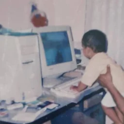 Gyanateet as a child, at a beige desktop computer